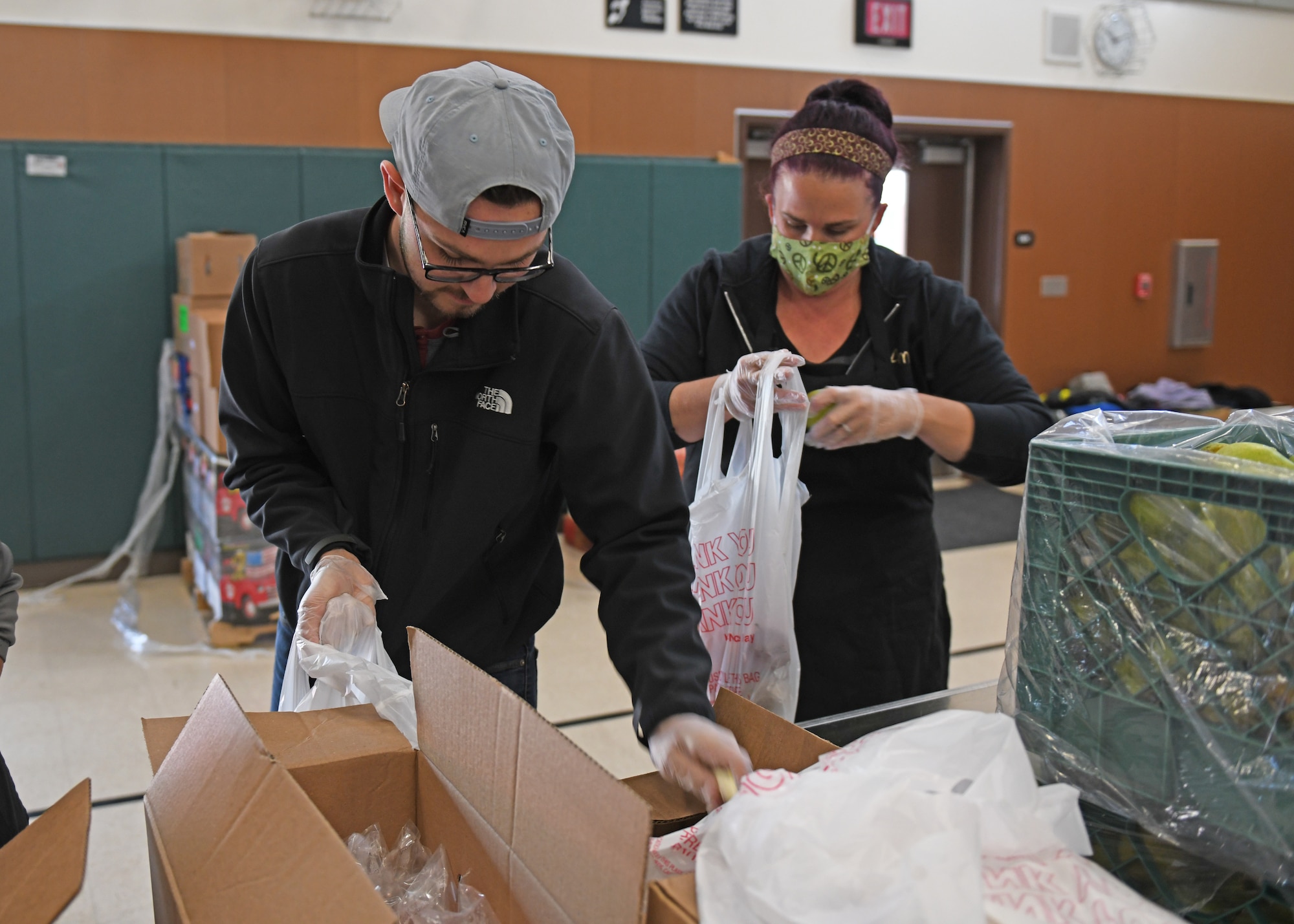 Senior Airman Ethan Morales, 9th Maintenance Squadron aerospace propulsion technician, loads up a bag with food, at a local elementary school in Olivehurst, California, April 6, 2020. Morales is helping the local school district package the bags to distribute them to students. (U.S. Air Force photo by Airman 1st Class Luis A. Ruiz-Vazquez)