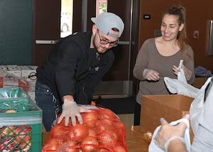Senior Airman Ethan Morales, 9th Maintenance Squadron aerospace propulsion technician, helps place a bag of onions on a table at a local elementary school in Olivehurst, California, April 6, 2020. The onions will be packaged into a bag that will be distributed to local students. (U.S. Air Force photo by Airman 1st Class Luis A. Ruiz-Vazquez)