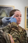 a woman soldier is receives a thermometer test at a National Guard facility