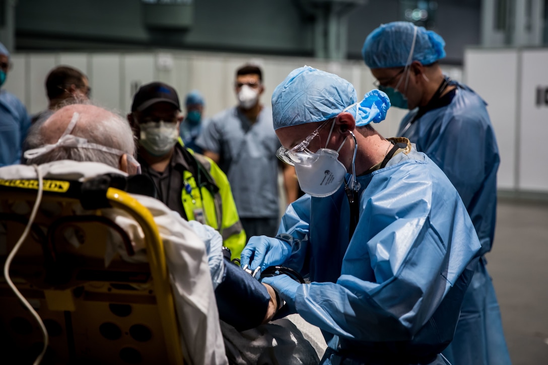 Persons in hospital scrubs interact with a patient.