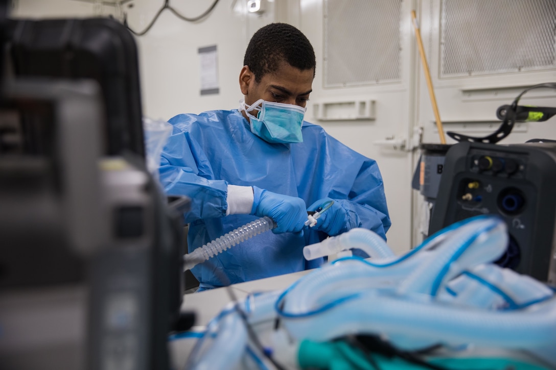 A man in hospital scrubs configures medical equipment.