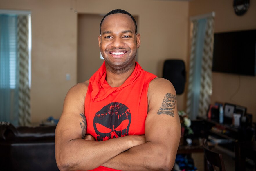 A U.S. Air Force chaplain poses in red and black workout attire at his home.