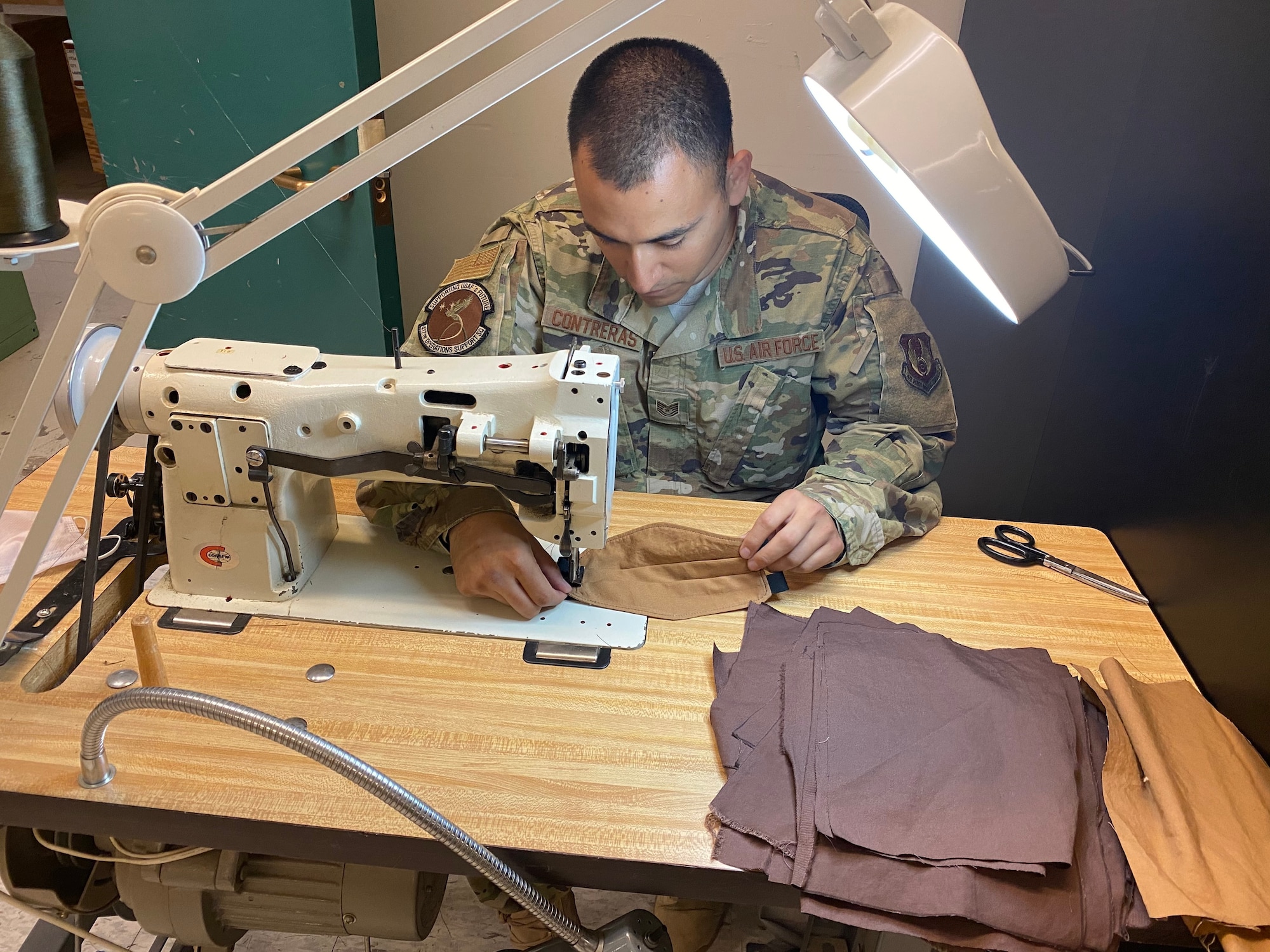 Tech. Sgt. Roman Contreras, quality assurance, air crew flight equipment, 412th Operations Support Squadron, 412th Operations Group, 412th Test Wing, fabricates a cloth mask using available equipment in the Air Crew Flight Equipment section at Edwards Air Force Base, April 7. Although cloth masks don’t offer full protection from COVID-19, the CDC advises that a simple cloth covering can slow the spread of the virus and help people who may have the virus and not know it from spreading it to others. (Courtesy photo)