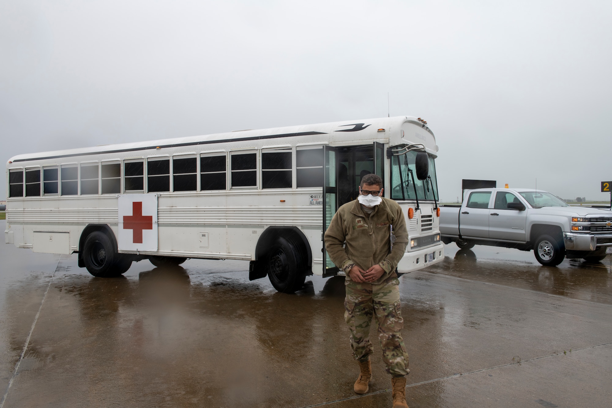 An Airman stands outside of a bus.