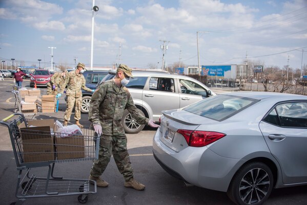 Indiana National Guard troops from the 381st Military Police Company, Plymouth, load groceries into cars of local families at a drive-thru food drive at the Food Bank of Northwest Indiana, Merrillville, Indiana, April 3, 2020.