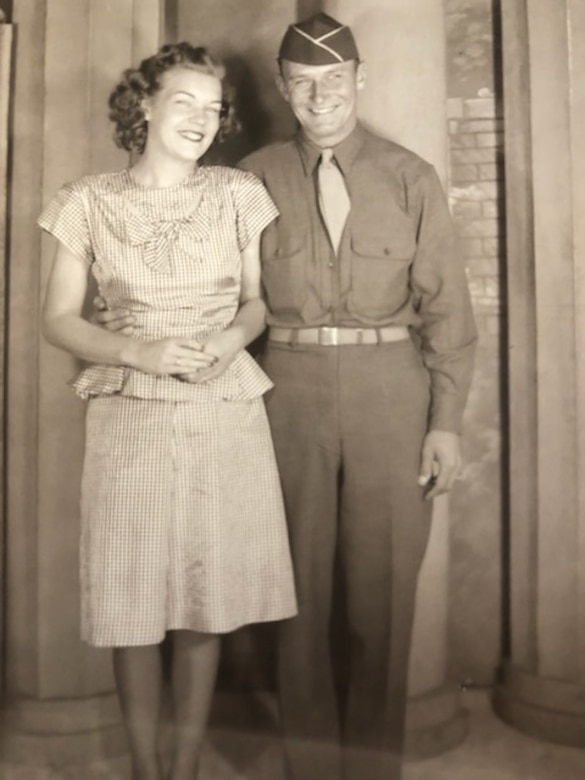A woman and a man in an Army uniform during the 1940s smile for the camera.