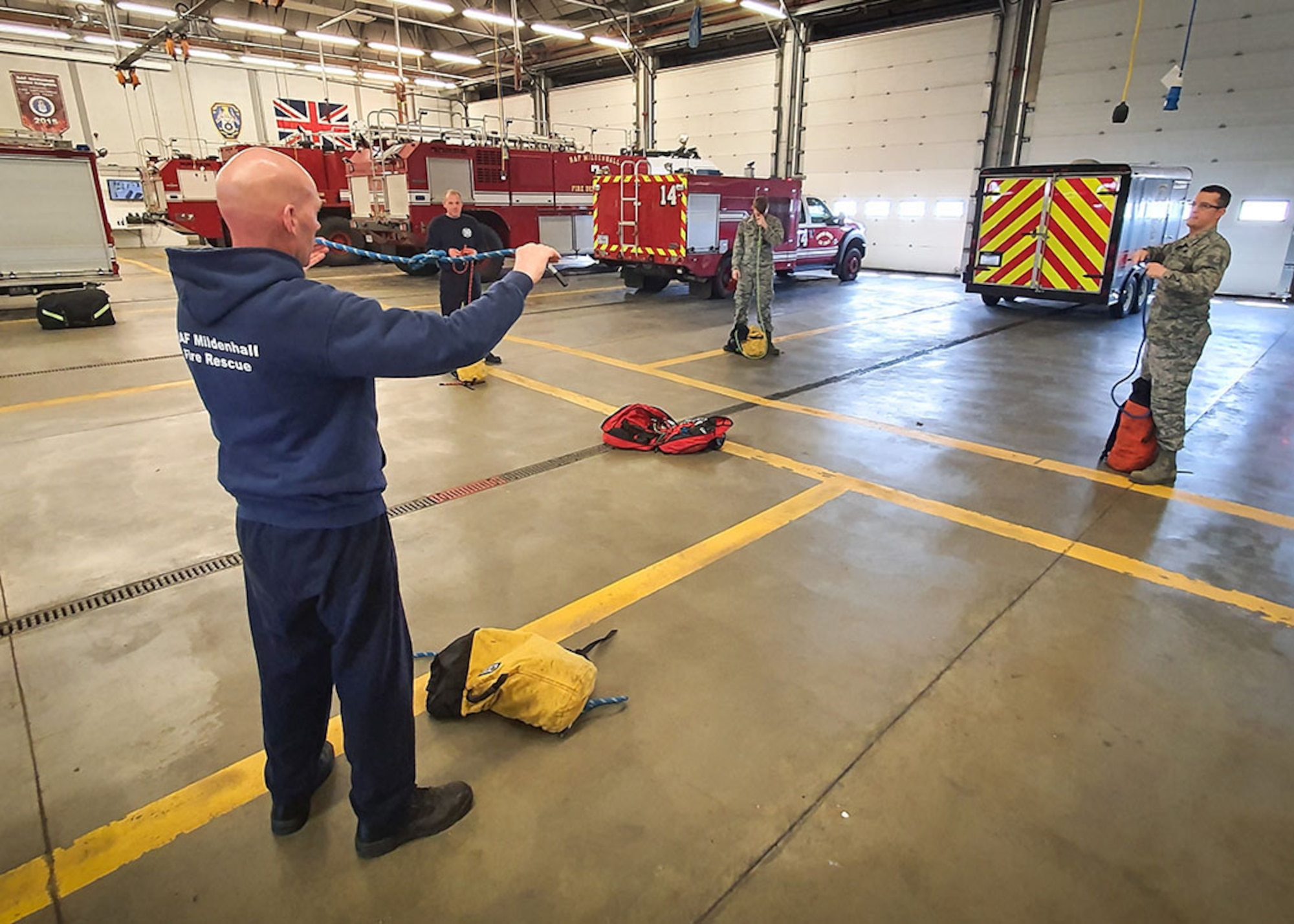 U.S. Air Force and civilian firefighters from the 100th Civil Engineer Squadron Fire Department carry out a rescue rope inspection while practicing physical distancing April 7, 2020, at RAF Mildenhall, England. During the COVID-19 lockdown, the firefighters are taking extra precautions both in and out of the fire station to ensure the health and safety of both themselves and the base community. (Courtesy photo by Matthew Thorpe)