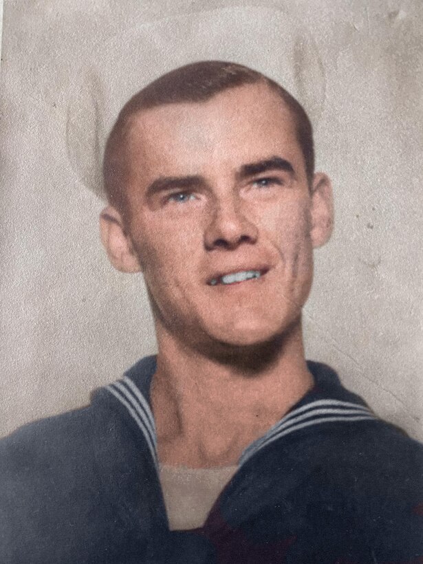 A young sailor in dress uniform smiles for an official photo.