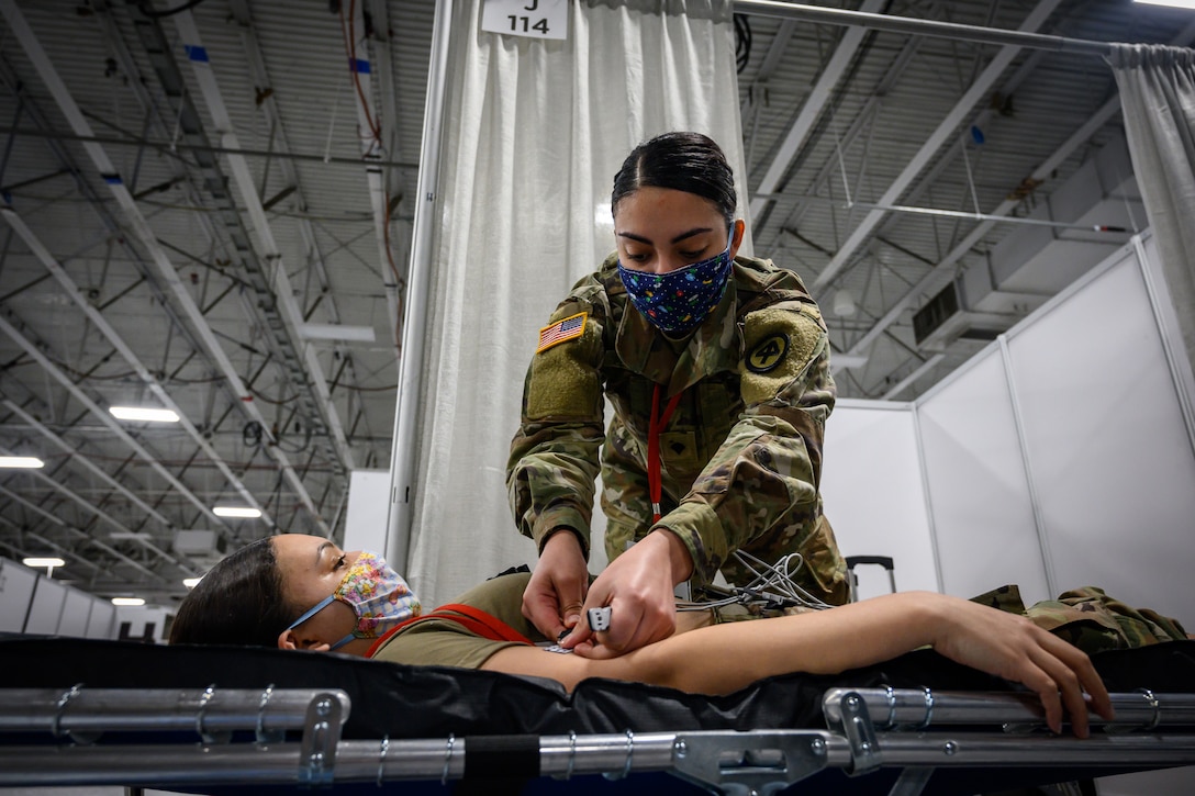 Soldier attaches electrodes to another soldier for an electrocardiogram.