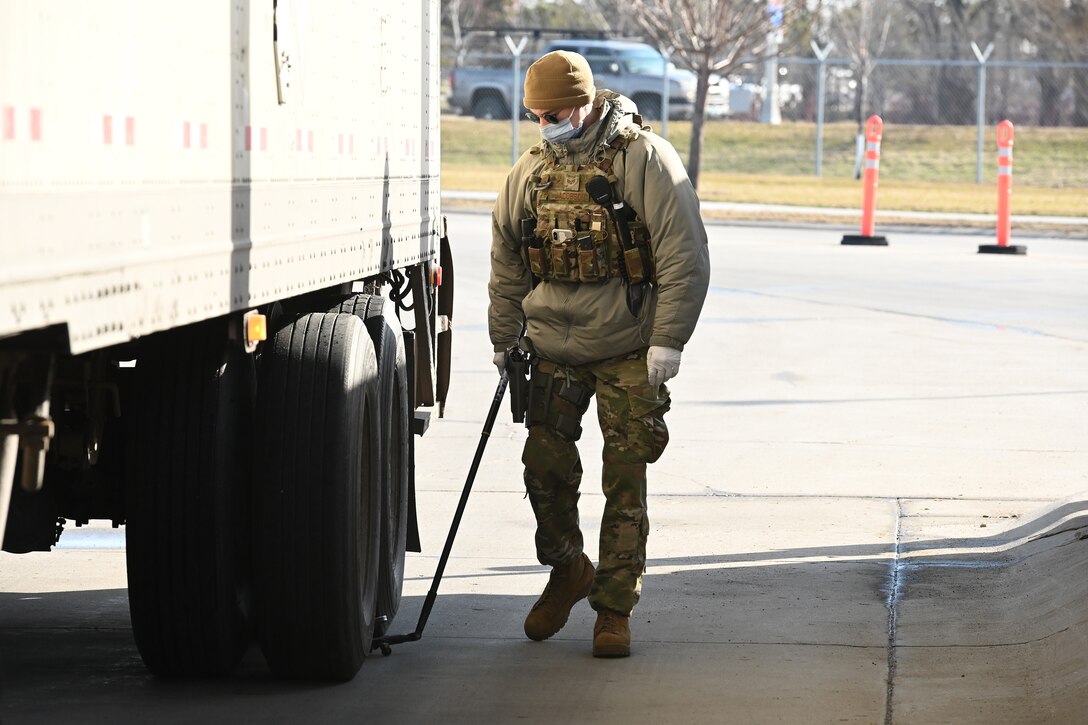 Photo of a 119th Security Forces Squadron member inspecting a commercial vehicle for entry at the gate of the North Dakota Air National Guard Base, Fargo, N.D., April 8, 2020. He is wearing personal protective equipment to help prevent the spread of the Novel Coronavirus.