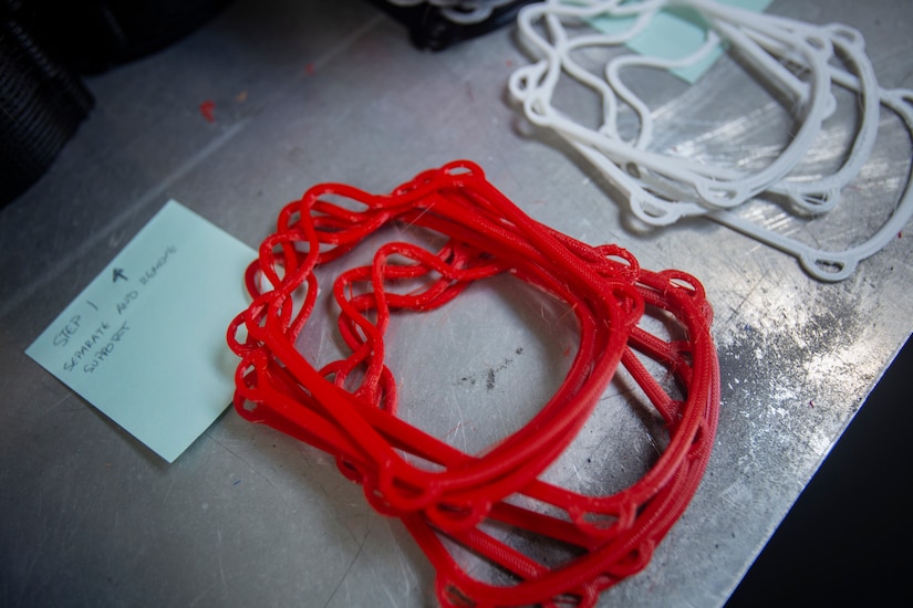 Red and white face mask frames are stacked on a workbench.