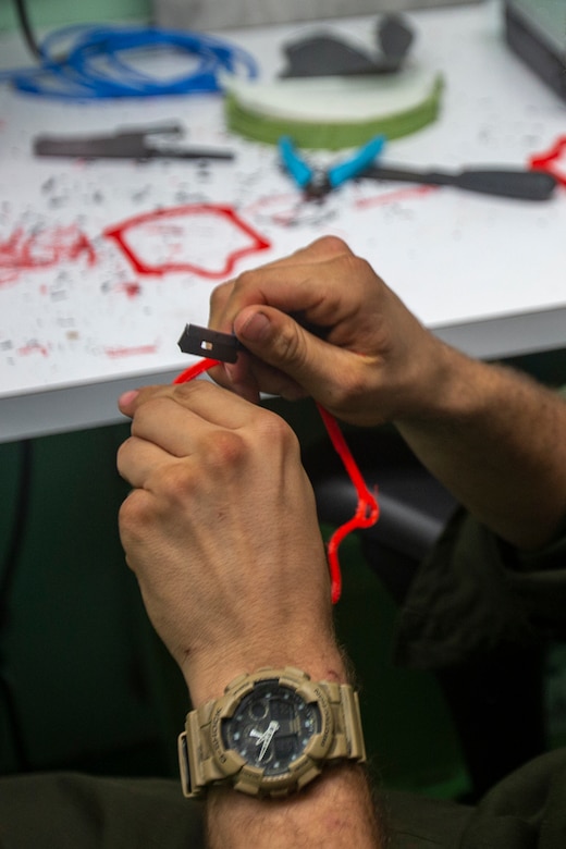 Close-up of excess plastic being trimmed from a 3D-printed face mask frame.