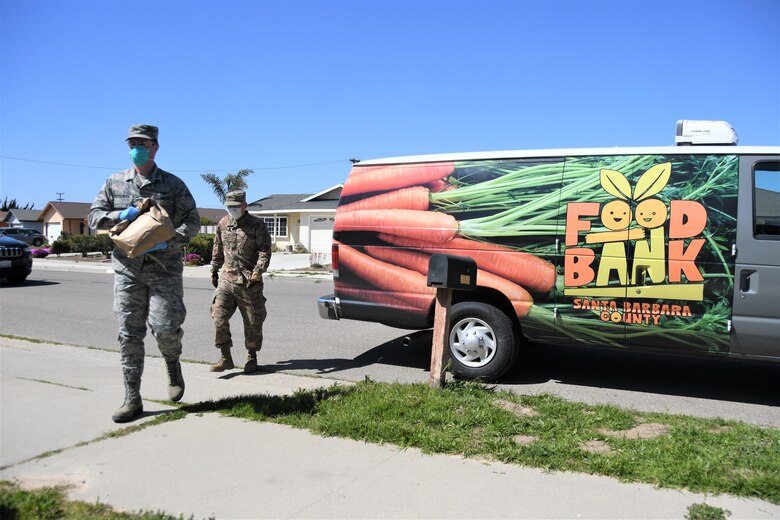 Airman 1st Class Soren Dietrichson, front, and Staff Sgt. Travis Emery, space operators for the California Air National Guard's 216th Space Control Squadron, deliver food to residences in Orcutt, California, on April 2, 2020, as part of the Cal Guard's COVID-19 humanitarian mission.