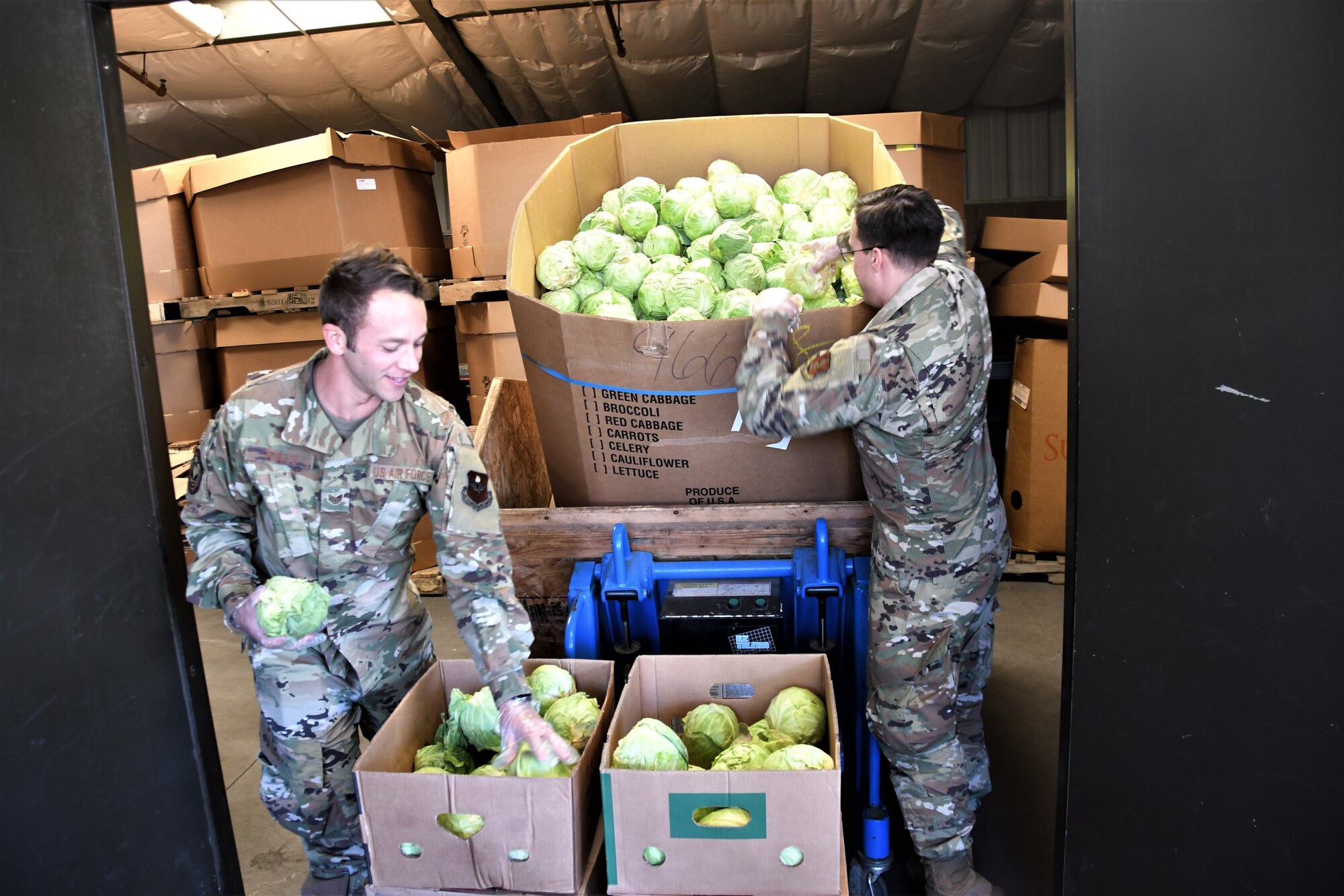 Staff Sgt. Brandon Tinges, left, and Airman 1st Class Carl Ritacco, space operators for the California Air National Guard's 216th Space Control Squadron, sort cabbages at the Food Bank of Santa Barbara County in Santa Maria, California, on April 2, 2020, as part of the California National Guard's COVID-19 humanitarian mission.