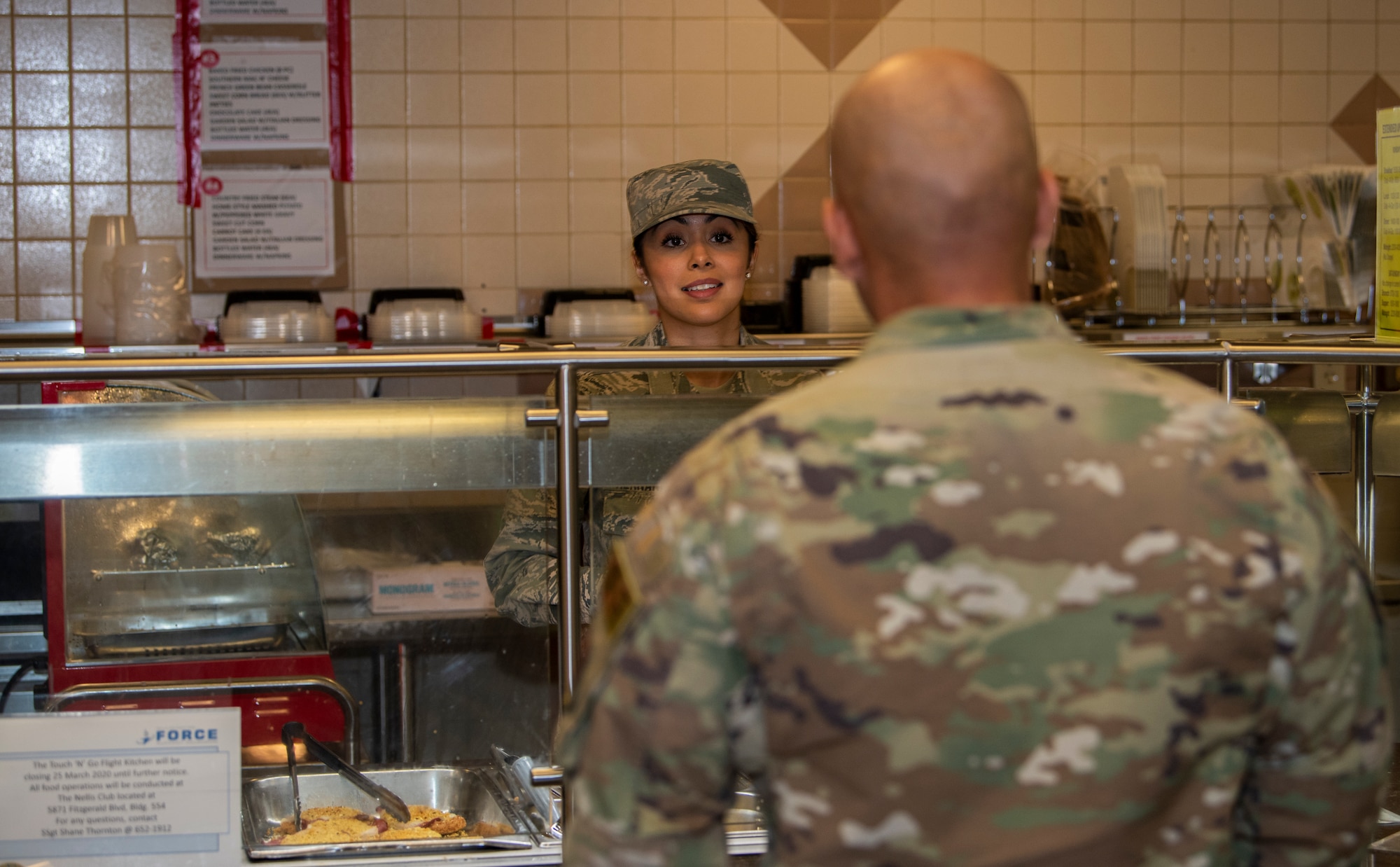 Airman serves food to another Airman in a lunch line.