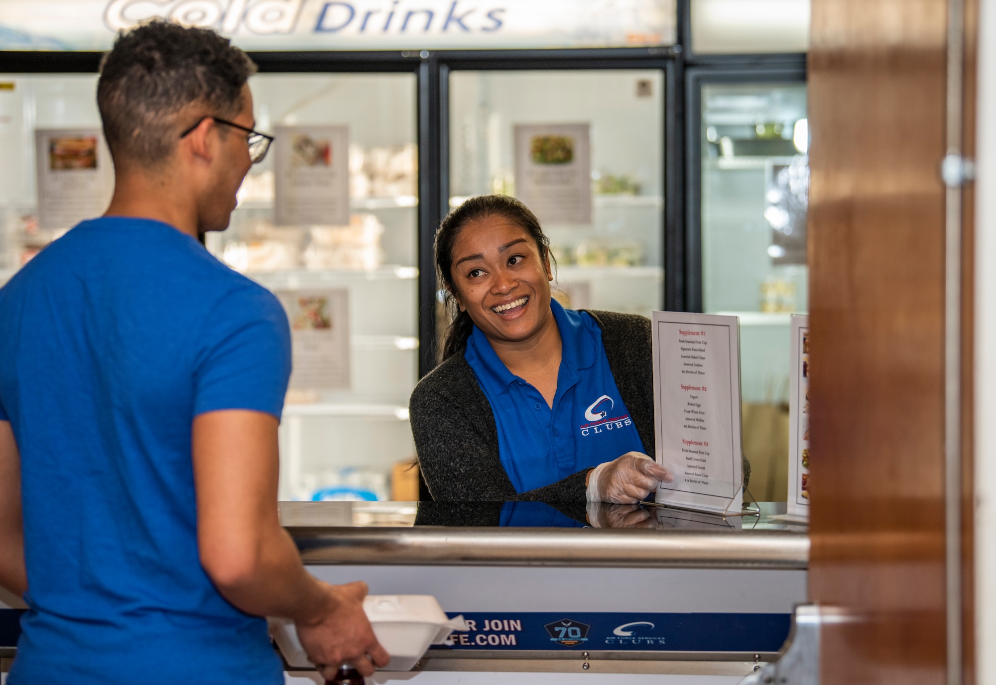 Worker shows menu options to customer.