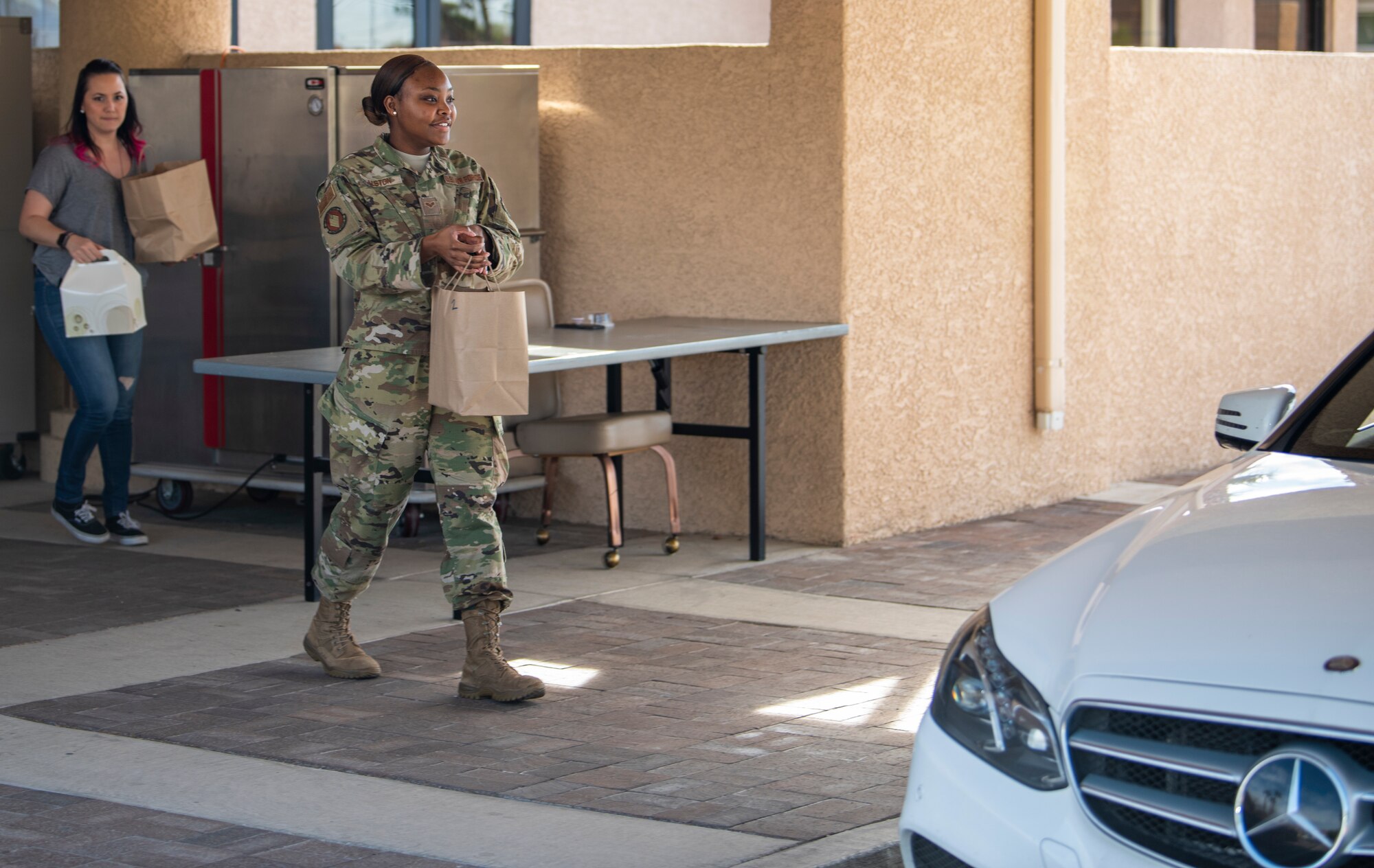 Airman and Civilian worker hand out to-go lunch order.