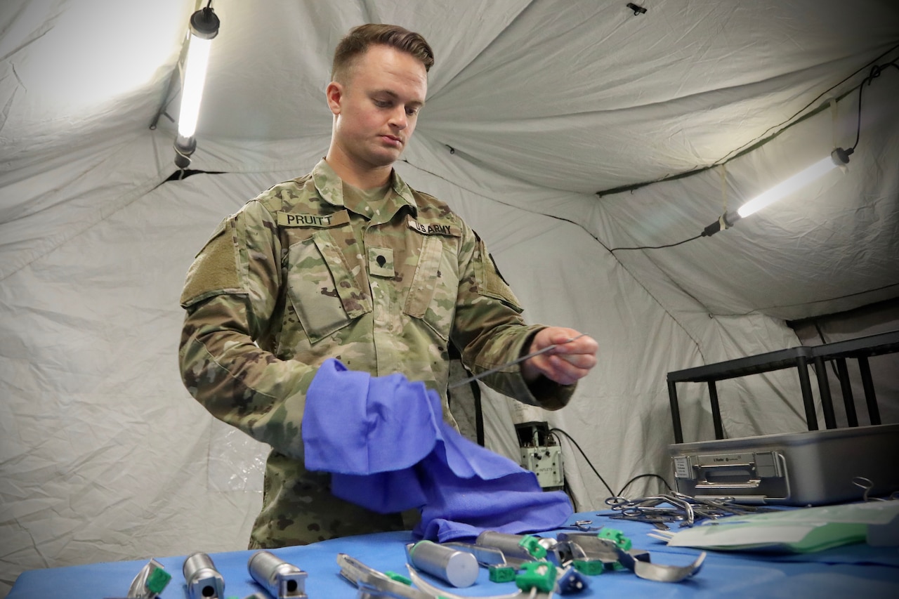 A service member uses a towel to dry a piece of medical equipment.