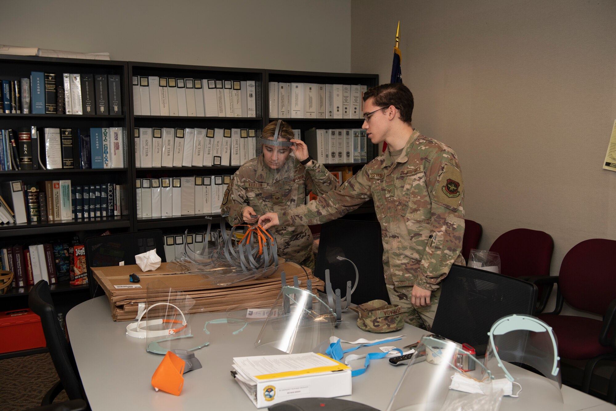 U.S. Air Force Staff. Sgt. Maximilion Estrada, right, Phoenix Spark noncommissioned officer in charge of agile manufacturing, discusses newly prototyped face shields with Staff Sgt. Kimber Keaton, 60 Medical Group Bioenvironmental Engineer craftsman, April 6, 2020, at Travis Air Force Base, California. The 60th Air Mobility Wing Phoenix Spark innovation cell has been working with other base organizations, the 60th Aerospace Medicine Squadron bioenvironmental engineering flight and the 60th Maintenance Squadron fabrication flight, since the beginning of March to deliver innovative personal protective equipment to Airmen amidst COVID-19. (U.S. Air Force photo by Senior Airman Jonathon Carnell)
