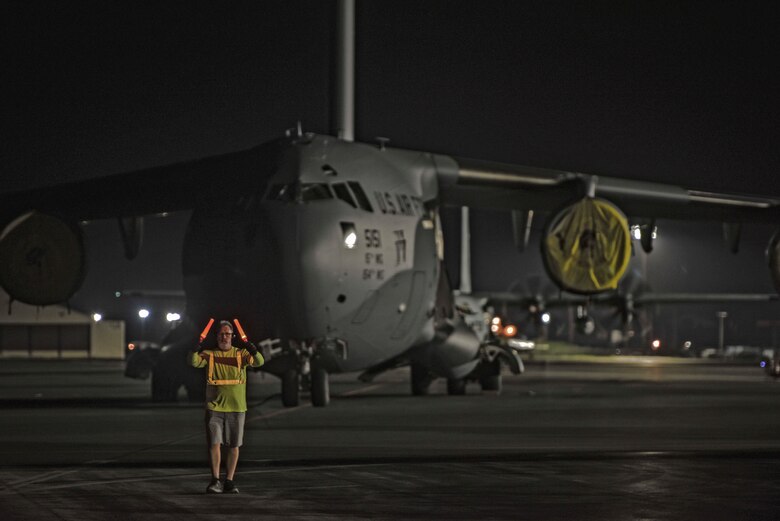 Bruce Miller, 735th Air Mobility Squadron Aircraft loader, spots a Tunner 60K loader driver on the flightline at Joint Base Pearl Harbor-Hickam, Hawaii, April  3, 2020. The 735th Air Mobility Squadron provided support to the Mariana Islands in response to the COVID-19 pandemic.  

 (U.S. Air Force photo by Tech. Sgt. Anthony Nelson Jr.)