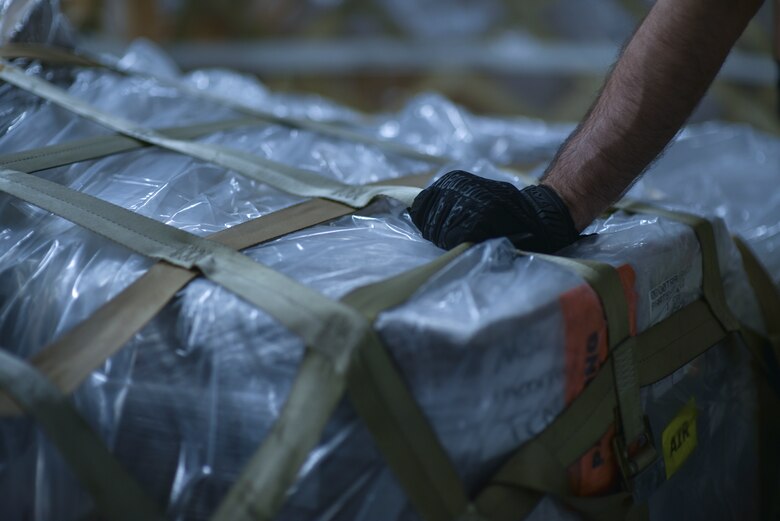 U.S. Air Force Staff Sgt. Charles Brown, 735th Air Mobility Squadron aircraft services supervisor, secures the top net of a COVID-19 pallet containing personal protective equipment and medical supplies on board of a  C-17 Globemaster III from the 535th Airlift Squadron at Joint Base Pearl Harbor-Hickam, Hawaii, April  3, 2020. The 735th AMS provided support to the Mariana Islands in response to the COVID-19 pandemic.  

 (U.S. Air Force photo by Tech. Sgt. Anthony Nelson Jr.)