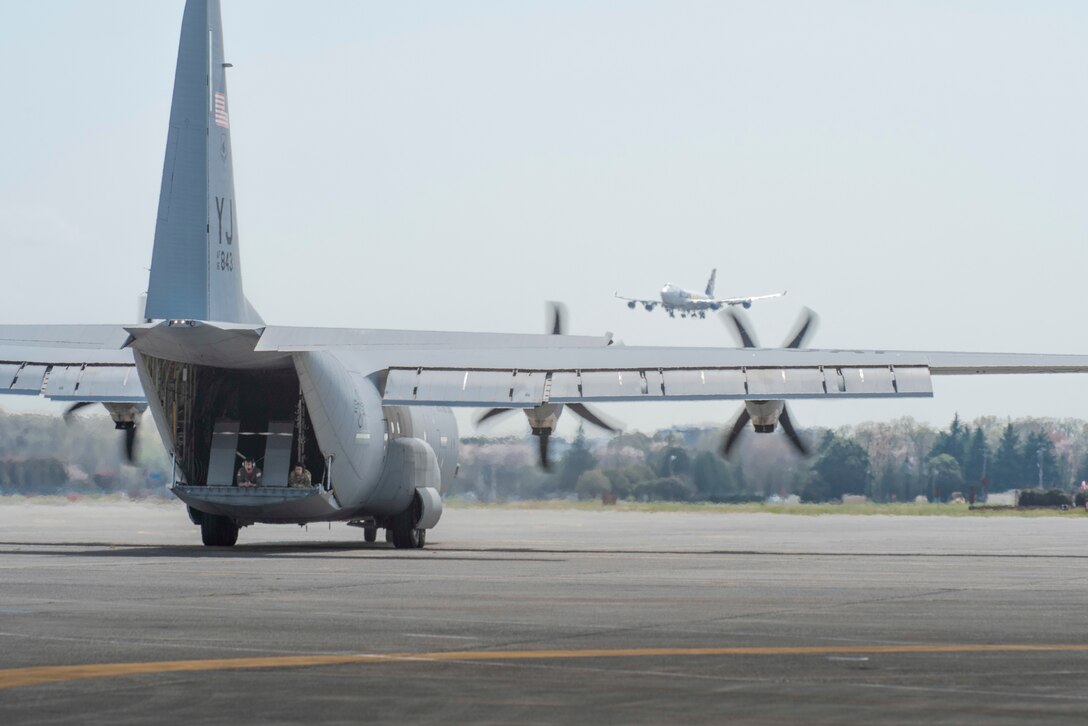 Senior Airman Jaime Suarez, left, and Senior Airman Antonio Parks, right, both 36th Airlift Squadron C‐ 130J Super Hercules loadmasters, guide a C‐130J pilot as the aircraft reverse taxis during the Yokota C‐130J Tactis Rodeo April 3, 2020, at Yokota Air Base, Japan.