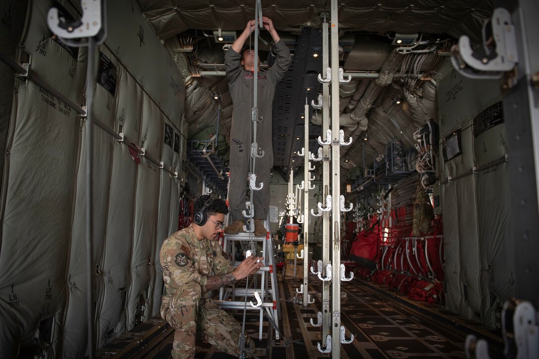 (From top to bottom) Senior Airman Jaime Suarez and Senior Airman Antonio Parks, both 36th Airlift Squadron C‐130J Super Hercules loadmasters, hang a litter strap in a C‐130J to execute an aeromedical evacuation scenario during the Yokota C‐130J Tactics Rodeo April 3, 2020, at Yokota Air Base, Japan.