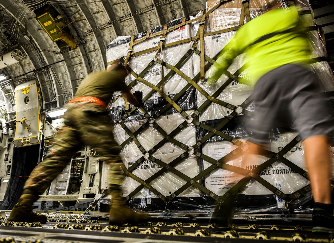U.S. Air Force Senior Airman Daniel Hofensperger and Bruce Miller, 735th Air Mobility Squadron personnel  moves COVID-19 personal protective equipment and medical supplies onto a  C-17 Globemaster III from the 535th Airlift Squadron at Joint Base Pearl Harbor-Hickam, Hawaii, April  3, 2020. The 735th AMS provided support to the Mariana Islands in response to the COVID-19 pandemic.  

 (U.S. Air Force photo by Tech. Sgt. Anthony Nelson Jr.)