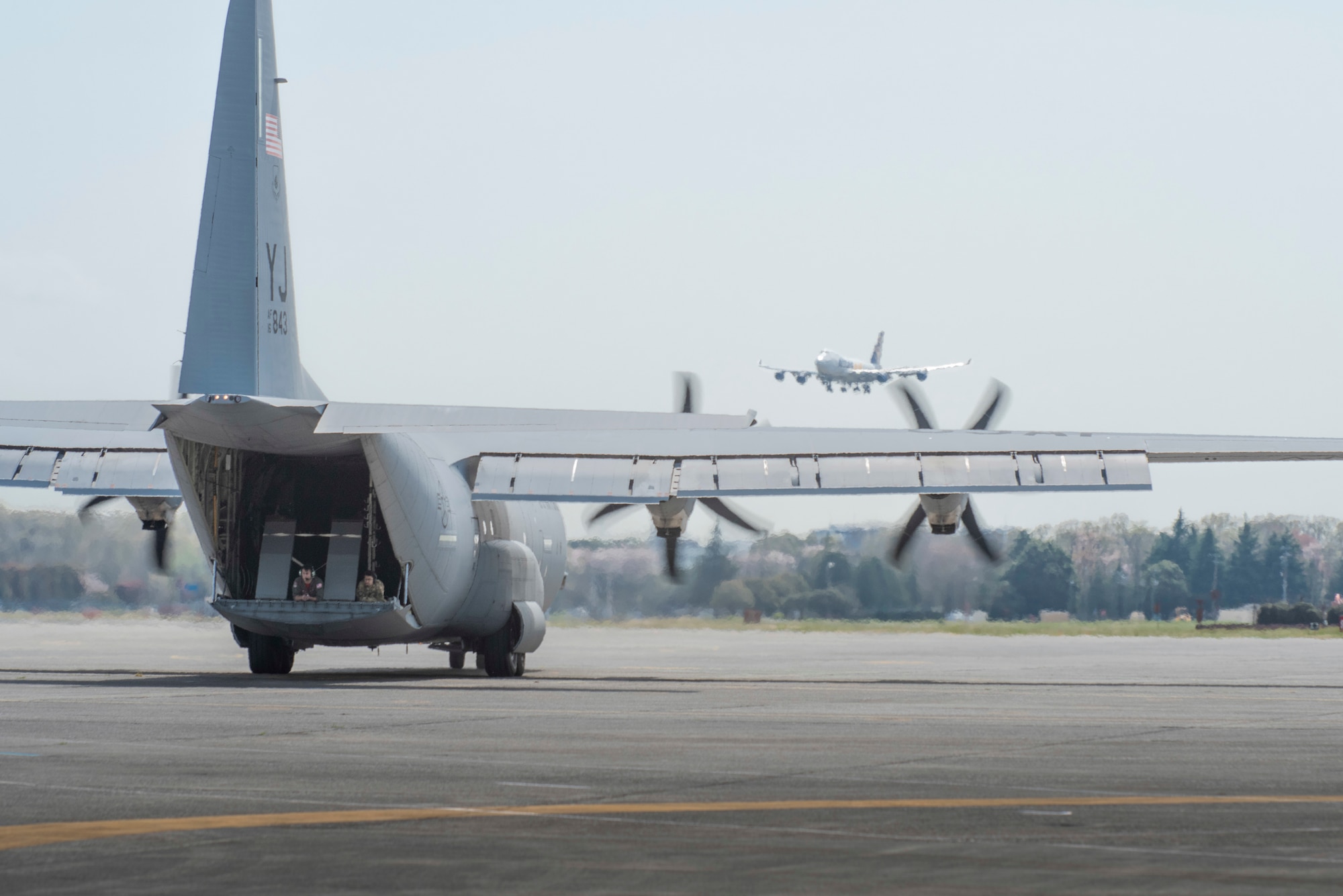 Senior Airman Jaime Suarez, left, and Senior Airman Antonio Parks, right, both 36th Airlift Squadron C‐ 130J Super Hercules loadmasters, guide a C‐130J pilot as the aircraft reverse taxis during the Yokota C‐130J Tactis Rodeo April 3, 2020, at Yokota Air Base, Japan.