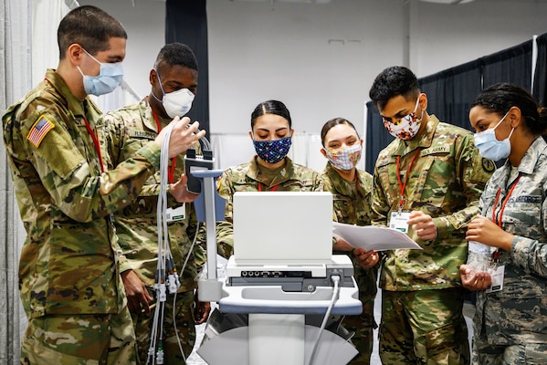 A group of guardsmen test medical equipment at a field medical station.