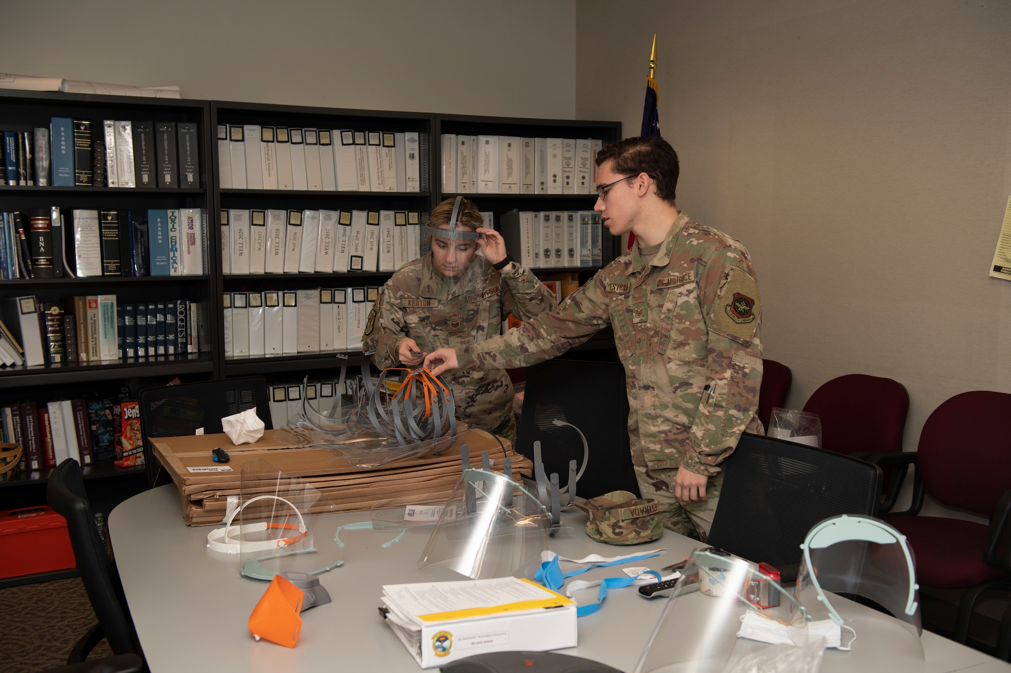 U.S. Air Force Staff. Sgt. Maximilion Estrada, right, Phoenix Spark noncommissioned officer in charge of agile manufacturing, discusses newly prototyped face shields with Staff Sgt. Kimber Keaton, 60 Medical Group Bioenvironmental Engineer craftsman, April 6, 2020, at Travis Air Force Base, California. The 60th Air Mobility Wing Phoenix Spark innovation cell has been working with other base organizations, the 60th Aerospace Medicine Squadron bioenvironmental engineering flight and the 60th Maintenance Squadron fabrication flight, since the beginning of March to deliver innovative personal protective equipment to Airmen amidst COVID-19. (U.S. Air Force photo by Senior Airman Jonathon Carnell)