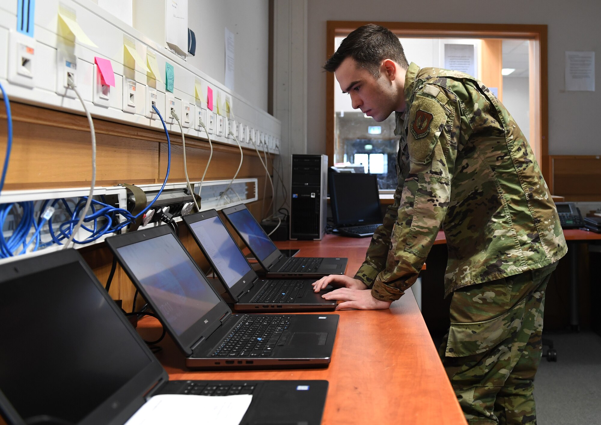 U.S. Air Force Airman 1st Class Wesley Carrow, 52nd Communications Squadron client systems technician, works on a computer in a back shop at Spangdahlem Air Base, Germany, April 6, 2020. Due to the spread of COVID-19, the 52nd CS received many computers that needed VPN capabilities added to support the amount of Airmen teleworking. (U.S. Air Force photo by Airman 1st Class Alison Stewart)