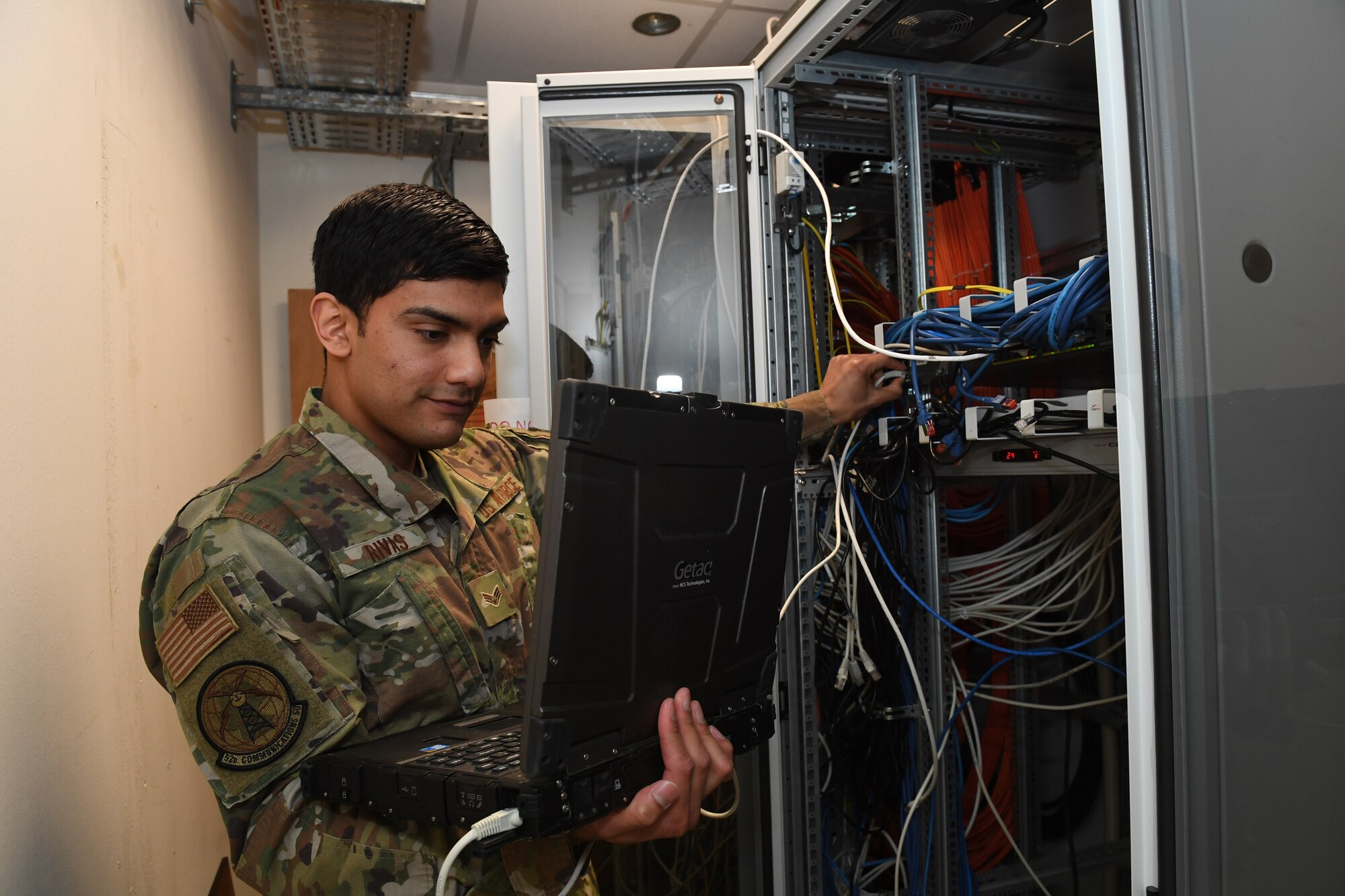 U.S. Air Force Senior Airman Mario Rivas, 52nd Communications Squadron cyber transport systems journeyman, plugs a computer into a server at Spangdahlem Air Base, Germany, April 6, 2020. Rivas makes in-person visits to squadrons that need switches configured in order to work remotely or to comply with physical distancing. (U.S. Air Force photo by Airman 1st Class Alison Stewart)