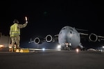 A 15th Aircraft Maintenance Squadron crew chief marshals a C-17 Globemaster III March 31, 2020, at Joint Base Pearl Harbor-Hickam, Hawaii. The aircraft returned to Oahu after transporting prematurely born twins from Osan Air Base, Republic of Korea, to Joint Base Andrews, Maryland, for care at Walter Reed National Military Medical Center. The C-17 was operated by a Hawaii Air National Guard aircrew from the 204th Airlift Squadron, augmented with a 15th Wing pilot from the 535th Airlift Squadron.
