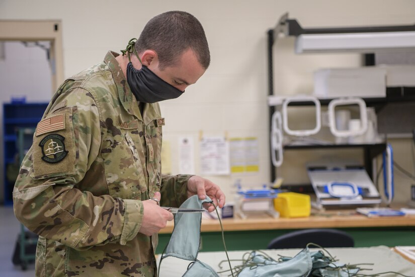 Staff Sgt. Matthew Kinard, 437th Operations Support Squadron aircrew flight equipment shift supervisor, cuts strings used to fasten face masks at Joint Base Charleston, S.C., April 8, 2020. The masks are intended to help mitigate the spread of infectious diseases. The shop started producing the masks earlier this week and have already made more than 500.