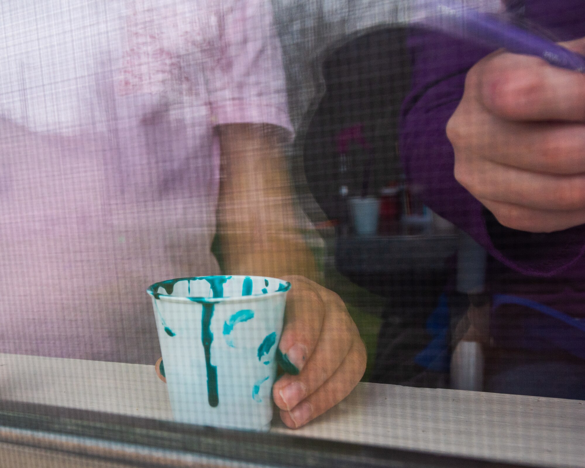 Gracie Carlton, 10, holds a cup of paint for her and her sister, Valorie, 8, April 6, 2020, at McConnell Air Force Base, Kansas. April is the Month of the Military Child, in dedication to children of military members who learn at a young age to adapt to the unique challenges of serving. The Carltons painted windows in their house to spend quality time together while physically distancing from others during the coronavirus outbreak. (U.S. Air Force photo by Staff Sgt. Chris Thornbury)