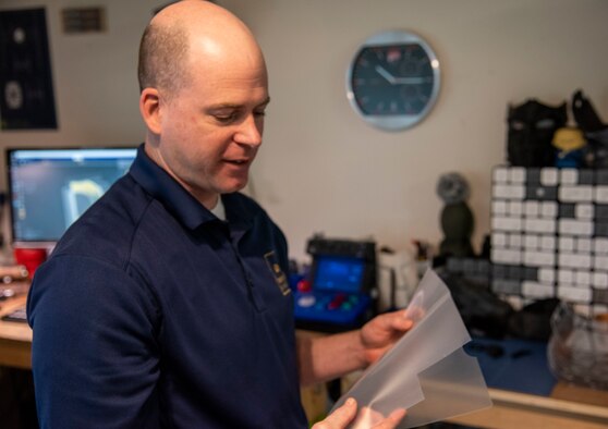 Master Sgt. Justin Pittman, innovation lab senior project manager, inspects laminant sheets used for face shields April 7, 2020, at Dover Air Force Base, Delaware. The face shields were printed by the 436th Airlift Wing Innovation Lab "Bedrock" for use by medical and security forces personnel supporting COVID-19 response efforts. (U.S. Air Force photo by Airman 1st Class Jonathan Harding)