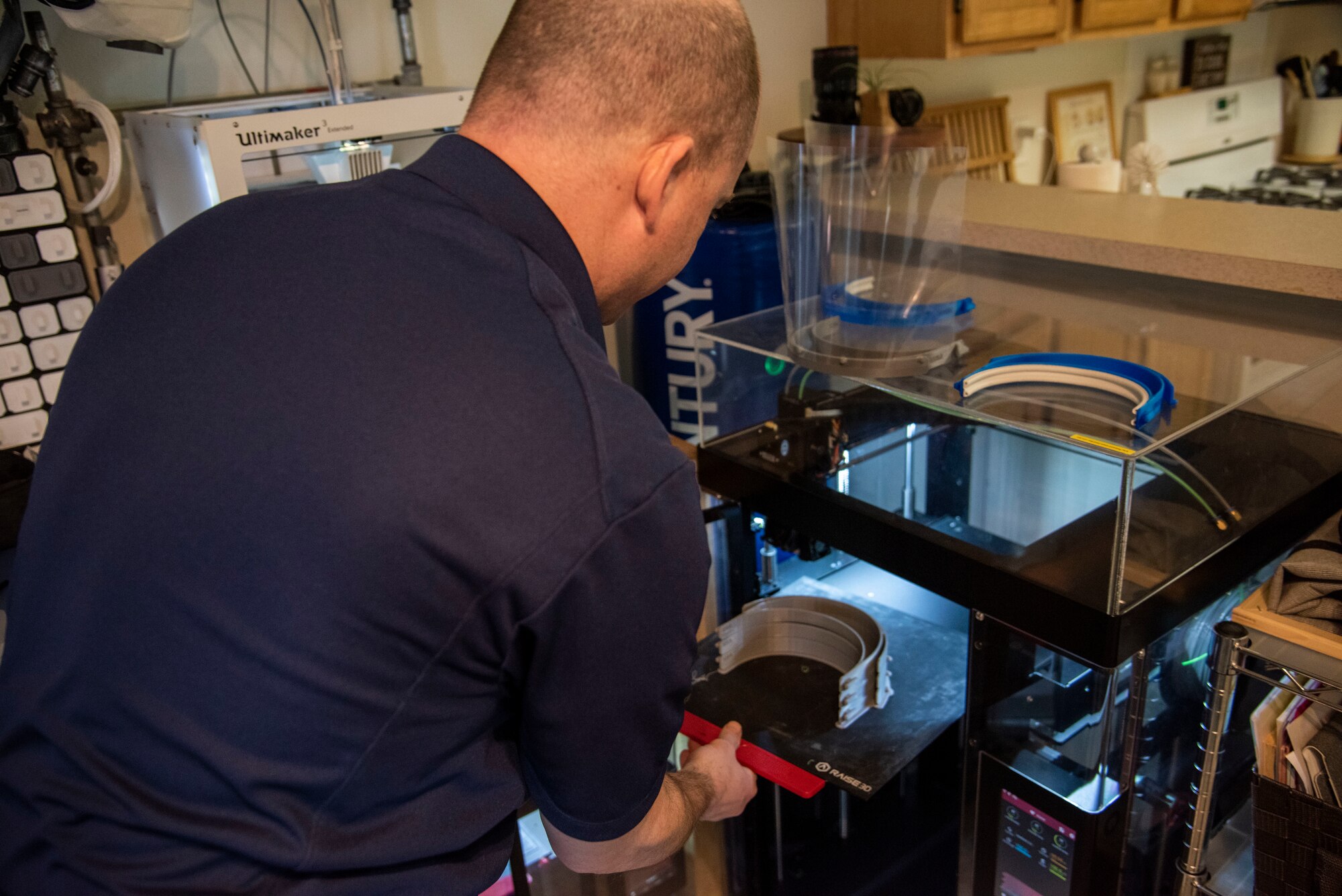 Master Sgt. Justin Pittman, innovation lab senior project manager, removes newly printed face shield headbands from a 3D printer April 7, 2020, at Dover Air Force Base, Del. The face shields were printed by the 436th Airlift Wing Innovation Lab "Bedrock" for use by medical and security forces personnel supporting COVID-19 response efforts. (U.S. Air Force photo by Airman 1st Class Jonathan Harding)