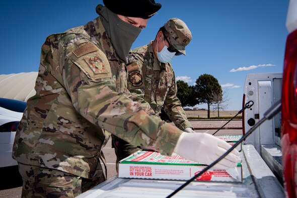 Tech. Sgt. Michael Jones, left, 50th Space Wing Inspector General’s Office wing exercise section chief, and Capt. Ronald Nguyen, right, 50th Space Wing Safety Office chief of safety, sanitize pizza boxes April 8, 2020, at Schriever Air Force Base, Colorado. Jones and Nguyen, both Joint Effort Delivery Initiative program volunteers, delivered 75 pizzas, donated by the USO, to mission essential Airmen working on base. (U.S. Air Force photo by Airman Amanda Lovelace)