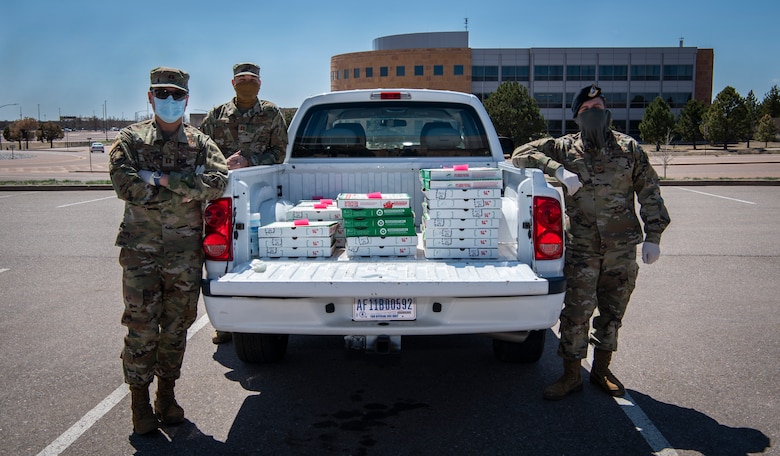 Capt. Ronald Nguyen, 50th Space Wing Safety Office chief of safety, front left, Capt. James Selix, 3rd Space Experimentation Squadron weapons and tactics flight commander, back left, and Tech. Sgt. Michael Jones, 50th Space Wing Inspector General’s Office wing exercise section chief, right, prepare to deliver donated pizzas April 8, 2020, at Schriever Air Force Base, Colorado. Selix’s wife, Aimee, came up with the idea to boost morale by delivering pizza to mission essential Airmen. She coordinated with the USO, which donated 75 pizzas, that were then delivered to Airmen through the Joint Effort Delivery Initiative program. (U.S. Air Force photo by Airman Amanda Lovelace)