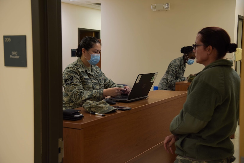 Photo of an Airman in-processing another Airman at a computer.