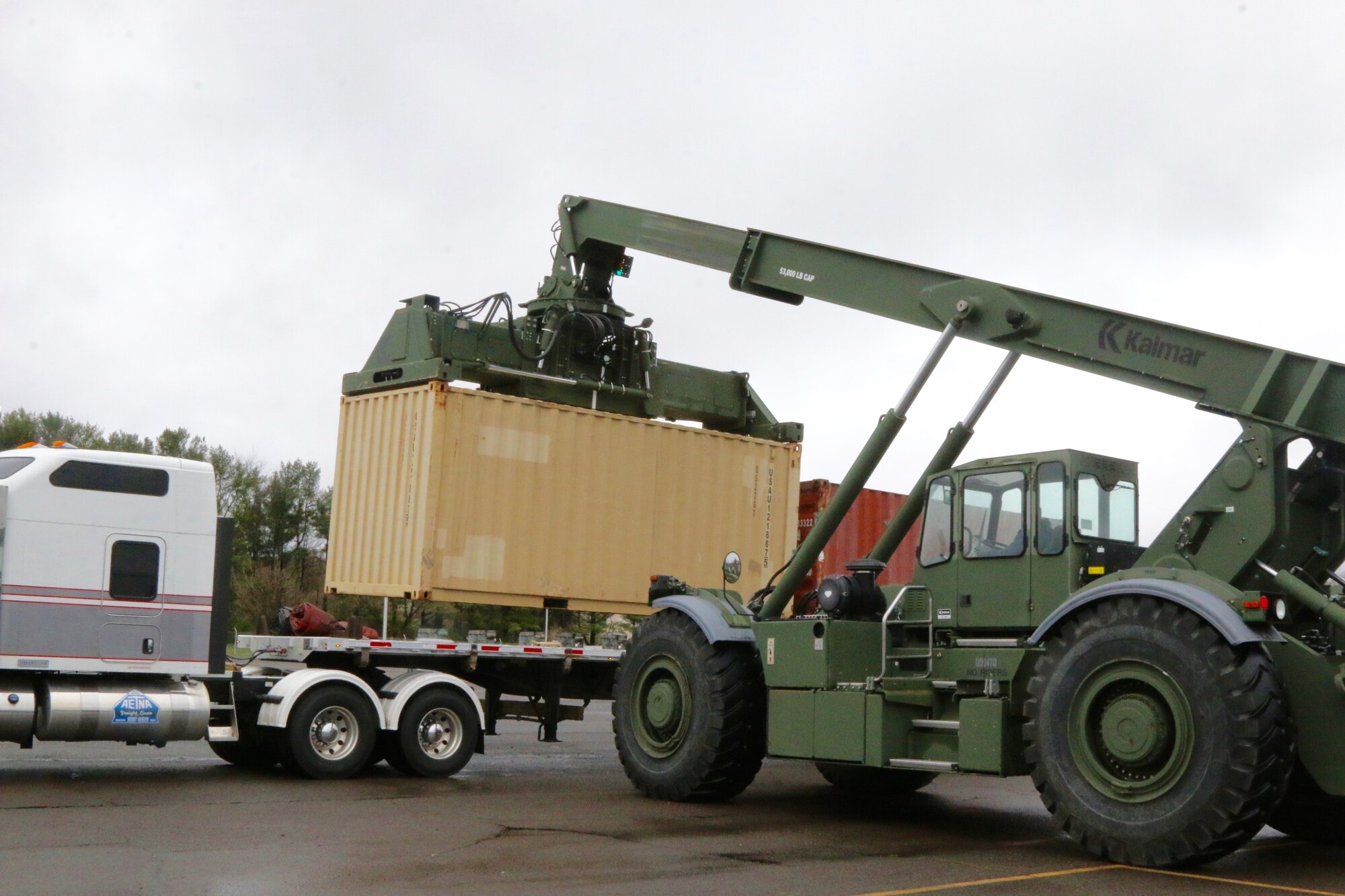Photo of a heavy machine downloading equipment from a truck.