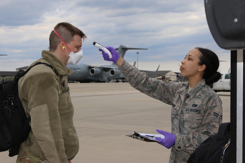 Photo of an Airman taking the temperature of another Airman.