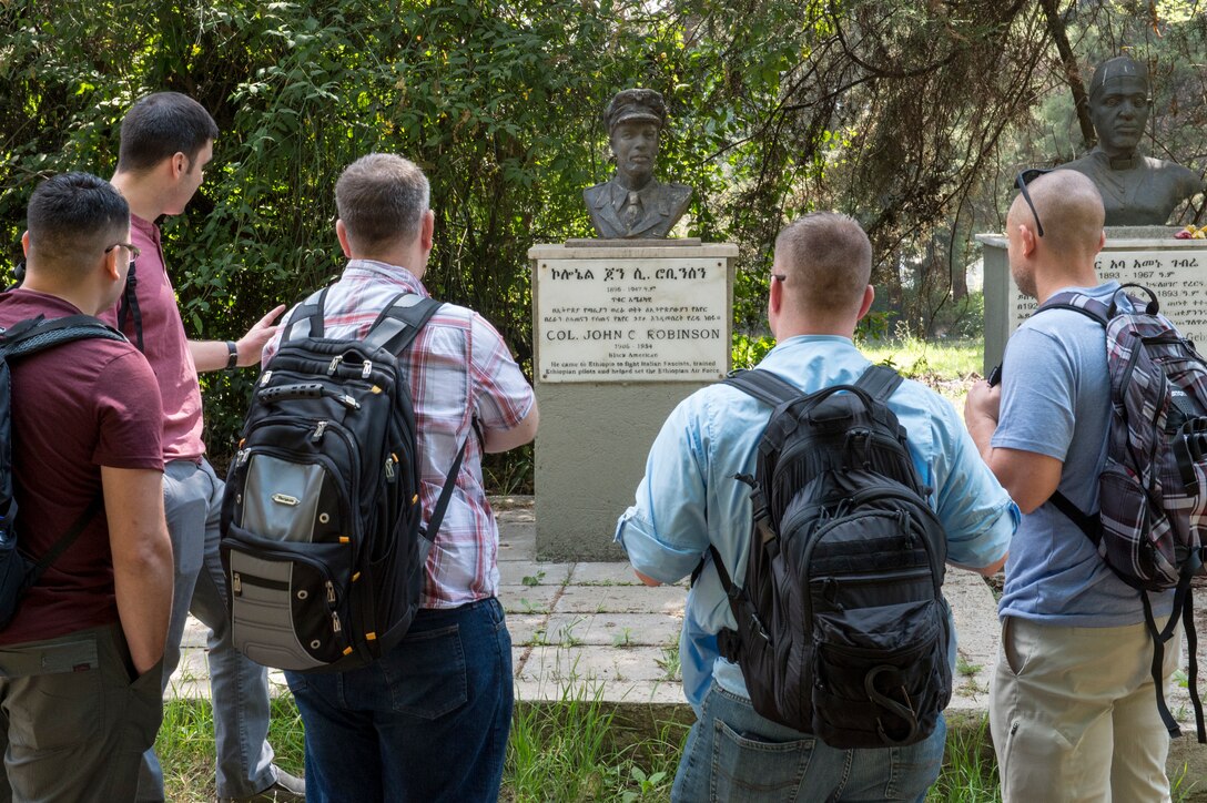 U.S. Airmen from the 818th Mobility Support Advisory Squadron visit the final resting place of John Robinson, a legendary aviator for Ethiopians and Americans, at Addis Ababa War Cemetery in Ethiopia Jan. 11, 2020. Every time Airmen from the 818th MSAS visit their Ethiopian counterparts for building partnership capacity missions, they make it a point to stop by the grave site of John Robinson, a legendary aviator in Ethiopian and American history, to honor the international relationship he cultivated.  (U.S. Air Force photo by Staff Sgt. Sarah Brice)