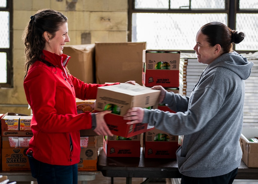 Photo of an individual passing on supplies to another person.