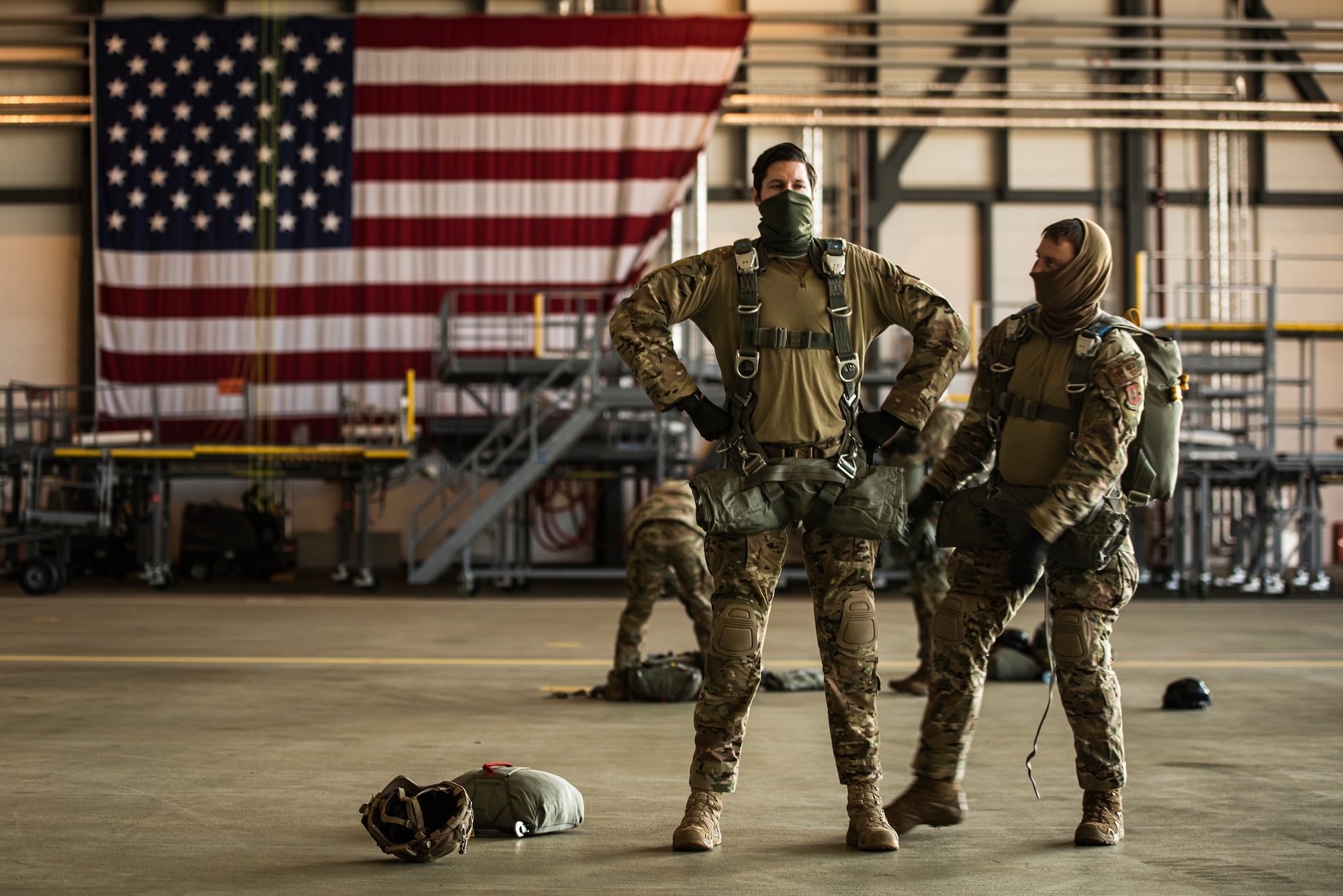 An Airman stands in a "superhero" stance in front of the American flag.