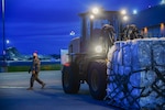 Two service members move a dolly loaded with boxes.