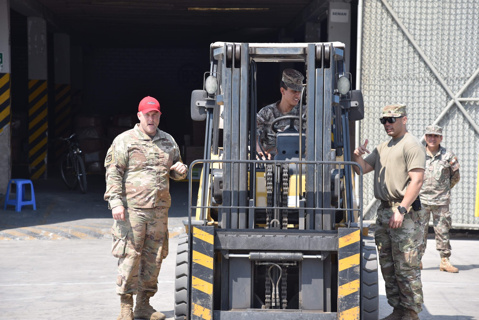 U.S. Air Force Tech. Sgts. Joseph Wruck, left, and James Garcia Arvelo, right, both air advisors from the 571st Mobility Support Advisory Squadron, teach Peruvian Air Force student Renato Rubén Figueroa Vasquez how to operate a forklift during a mobile training team mission with the Peruvian Air Force at Callao Air Base in Lima, Perú. The MTT included three weeks of instruction at Callao and covered three general areas: an introduction to aerial logistics and logistical management mindset, hazardous material management, and cargo loading. (courtesy photo)