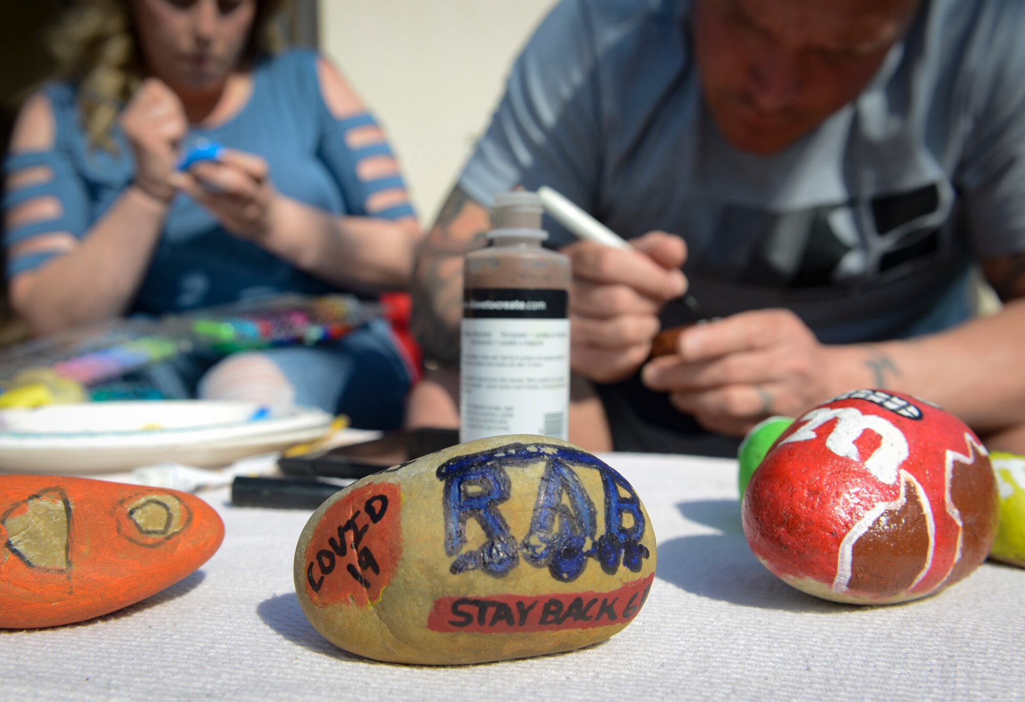 Danyelle Gentry, left, Ramstein Elementary School front office assistant, and her husband, Master Sgt. Garett Gentry, 786th Civil Engineer Squadron section chief, paint rocks to place around the community at Ramstein Air Base, Germany, April 7, 2020.