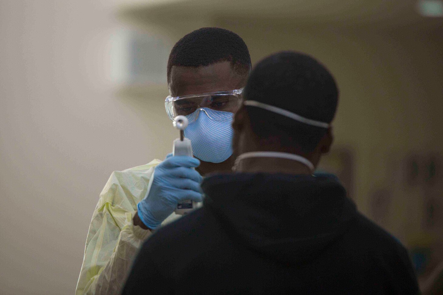 U.S. Hospital Corpsman 3rd Class Tavish Davis with 3rd Medical Battalion, 3rd Marine Logistics Group, tests a USS Theodore Roosevelt (CVN 71) Sailor for symptoms of COVID-19, on Naval Base Guam, Guam, April 8, 2020. Theodore Roosevelt is in Guam for a scheduled port visit for resupply and crew rest during their scheduled deployment to the Indo-Pacific.